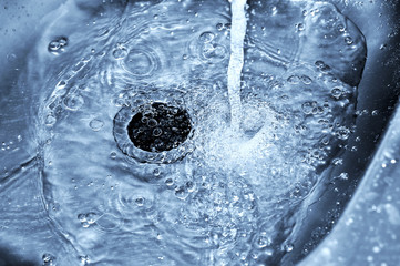 Stream water flows into the stainless steel sink (blue tones)