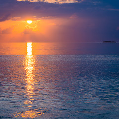 Fine art of sunset. A bright fantastic sunset in the tropics. The sun sets over the horizon of the ocean.  Image is an abstract illustration or painting, fine art.