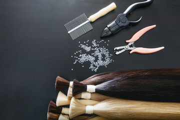 Set of sevral color hair extension tools on a dark background - 166863798