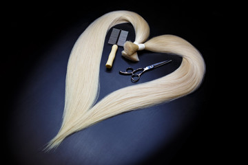 hair extension equipment of natural blonde hair. heart shape on a dark background.
