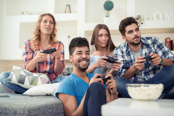 Smiling friends playing video games at home