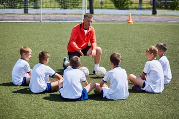 Fotobehang Voetbal Coach Instructing Junior Football Team in Practice  © Seventyfour