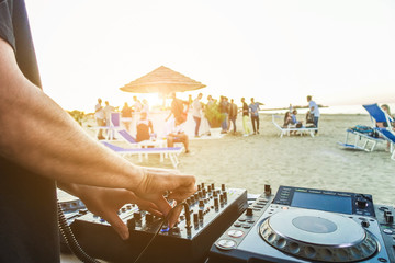 Dj mixing at sunset beach party in summer vacation 