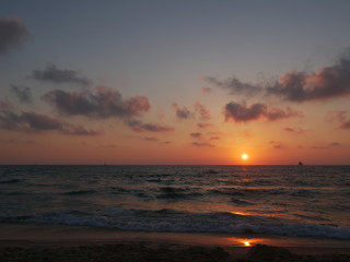 Dramatic sunset with clouds over mediterranean sea, yacht and ship on horizon, Tel Aviv, Israel.