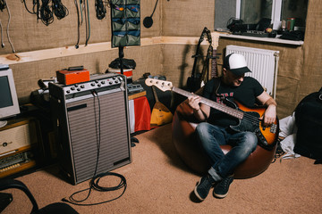 Guitarist in old garage recording studio. Messy music basement with instruments, album making...