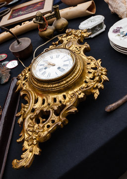 Old golden clock and other antiquities at flea market in Paris (France)