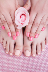 Nail spa procedure. Manicure and pedicure. Female hands and feet on pink background top view. Result of spa salon procedure