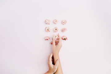 Girl's hand holding pink dry rose buds on pink background. Flat lay, top view. Flowers background.