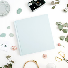 Fototapeta na wymiar Blue family or wedding photo album with blank space for text, eucalyptus leaf, retro camera and dry rose buds on white background. Flat lay, top view.