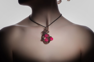 a beautiful handmade pendant with an awesome red stone on the woman's neck