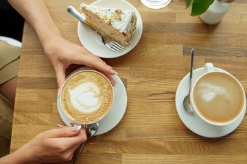 cup of coffee in a cafe and a girl's hands. Close-up of woman's hands, sitting with cup of coffee in coffee house