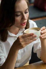 Close up of young beautiful woman drinking coffee at the coffee shop.