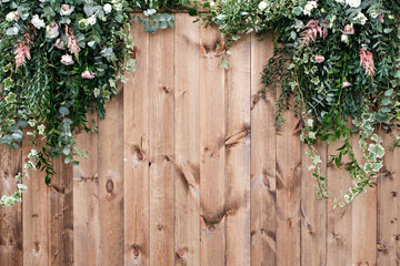 Fototapeta na wymiar Fresh spring greens with white flower and leaf plant over wood fence background