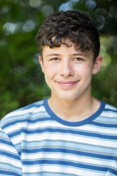 Portrait Of Happy Teenage Boy Sitting Outdoors