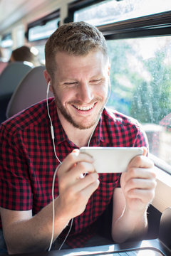 Man Watching Movie On Mobile Phone During Journey To Work