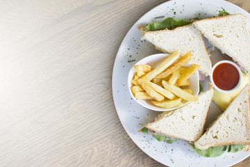 Club sandwich with chicken breast, bacon, tomato, cucumber, and herbs. French fries on the side.