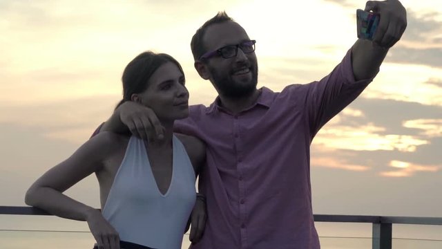 Young couple taking selfie photo with cellphone on balcony 
