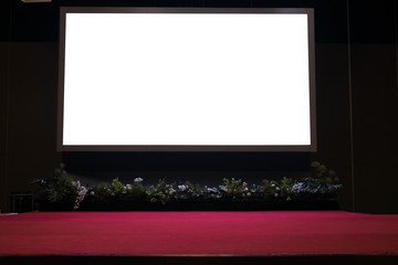 projector screen on stage with red carpet in conference hall.