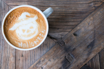 halloween latte art on hot cappuccino coffee in white mug on wood table