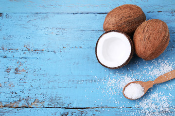 Coconuts with flakes in spoon on blue wooden table
