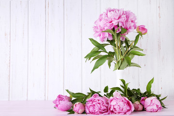 Bouquet of peony flowers in vase on pink wooden table