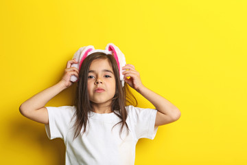 Fototapeta na wymiar Beautiful little girl with rabbit ears on yellow background