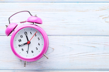 Pink alarm clock on white wooden table