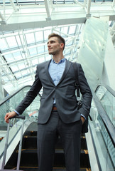 Businessman at the airport going down the escalator.