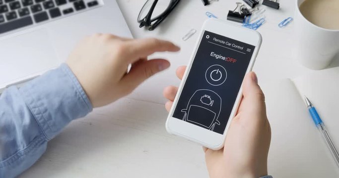 Man remotely starts engine of his car. Car remote control using smartphone application fictional interface.