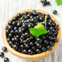 Fresh berries in a bowl on wooden garden table. Selective focus, space for text.