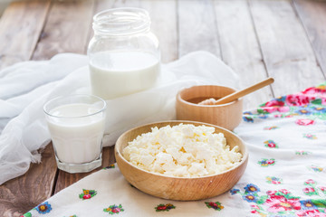 Cottage cheese in a wooden bowl on a background of cans of milk