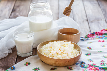 Cottage cheese in a wooden bowl on a background of cans of milk