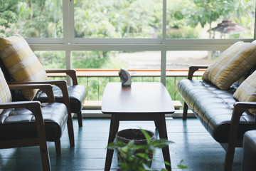 table, chair and leather sofa near window with garden view at restaurant cafe coffee shop