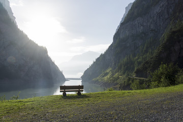 Ruhebank mit Aussicht auf Stausee im steilen Bergtal