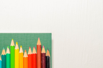 Color pencils, notebook on white background, top view