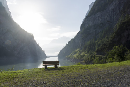 Ruhebank mit Aussicht auf Stausee im steilen Bergtal