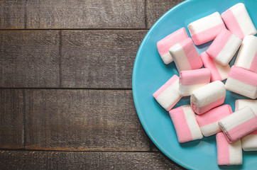 Pink marshmallows on a dark background in a blue plate