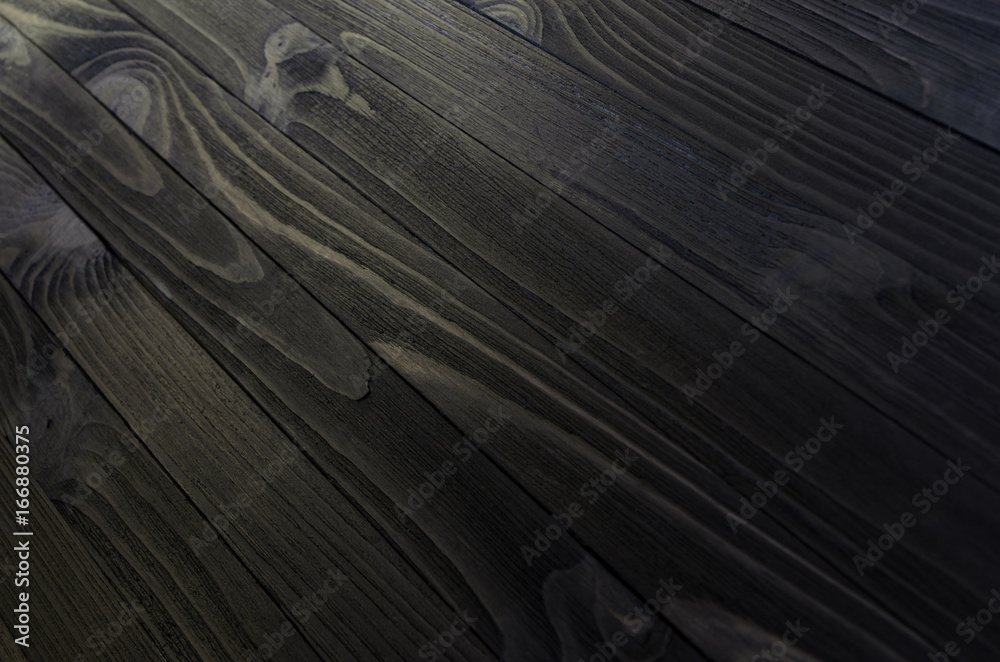 Wall mural black wood texture close-up. shield from diagonally directed boards with wavy pattern of fibers.