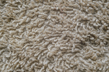 Macro shot of a beige color towel. Texture is similar to the texture of a fleecy knotted-pile carpet. Chaotic pattern of villi on fabric material.