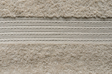 Element of beige color towel. Fleecy part and decorative element with braided pigtails. Texture is similar to the texture of a fleecy knotted-pile carpet.