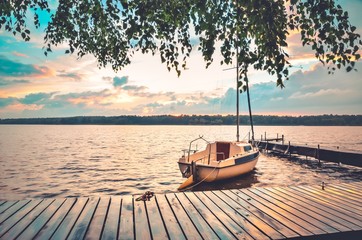 Boat and wooden pier on a beautiful lake. Evening summer landscape by the water.