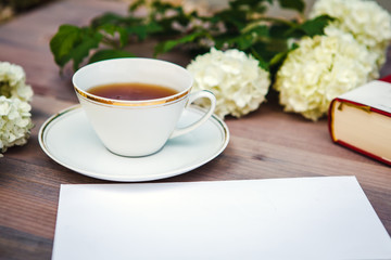 Cup of tea on a wooden table, with white flowers Guelder-rose, still life