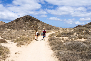 Surfer hiking in the small island Isla Los Lobos Fuerteventura.