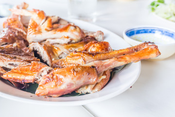 Closeup of grilled chicken on white dish and table for lunch or dinner.