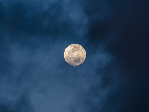 Mystic glowing moon with clouds in blow grey sky.
