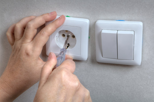 Electrician hands installing electrical wall sockets, and light switch, close-up.