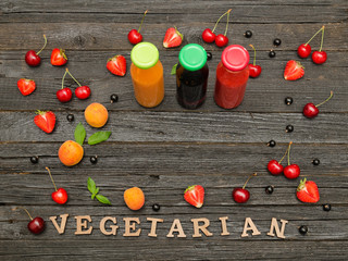 Three bottles with juice, fruit and inscription vitamins on a wooden background, food concept