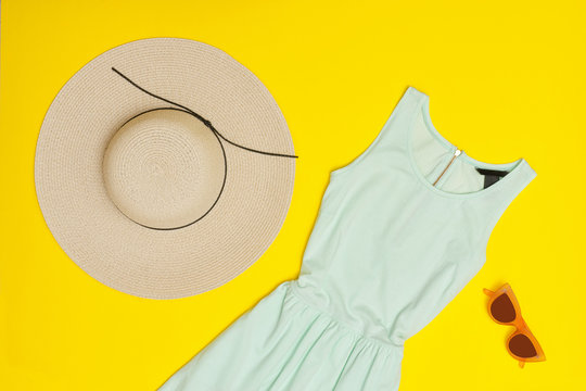 Fashionable concept. Female summer wardrobe. Mint dress, hat, glasses. Yellow background, top view