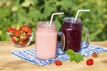 Strawberry, raspberry, blackberry and banana juice smoothie shake in two glass mug, outdoors, close up