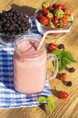 Strawberry, raspberry, blackberry and banana juice smoothie shake in glass mug, outdoors, close up